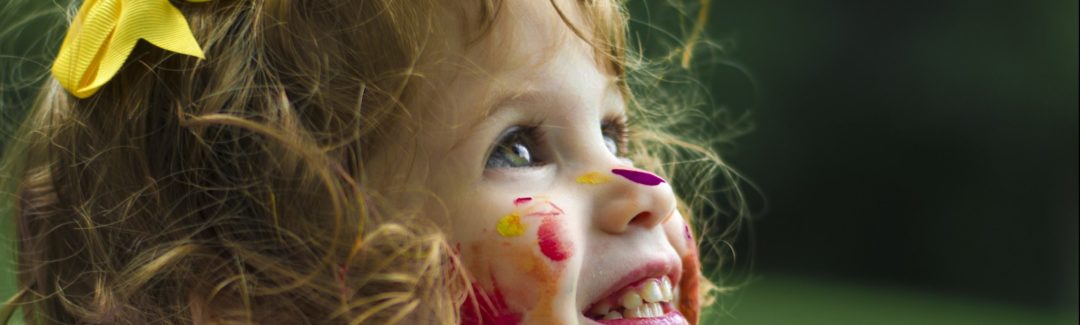 young child with face covered in paint; highlighting the Canada Child Benefit offerings