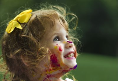 young child with face covered in paint; highlighting the Canada Child Benefit offerings
