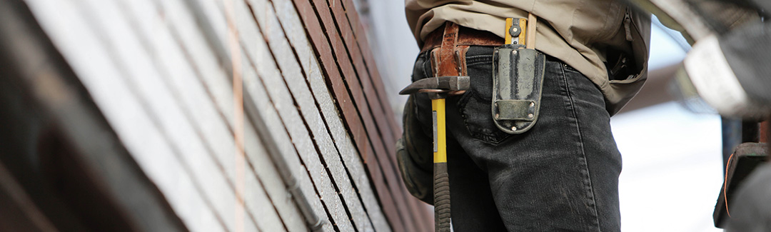 Construction worker closeup with tool belt and house siding; highlighting how to pay yourself from an incorporated business