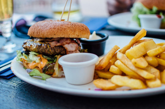 Bacon cheeseburger and fries on a plate highlighting writing off meal expenses