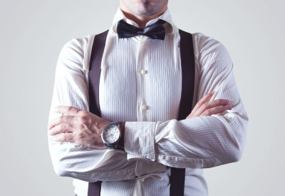 Closeup of a single man with arms crossed wearing a shirt, suspenders, and bow-tie; highlighting a personal services corporation